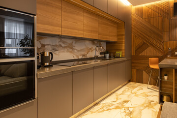 Interior details. Kitchen in a modern apartment. Natural materials. Household appliances, kettle, coffee machine, built-in oven, microwave. Bar counter, high chair. Designer wood panel on the wall