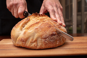 Sourdough bread loaf being cut after being baked in the oven
