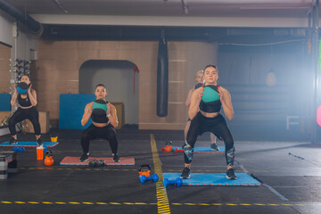 Fitness group of four attractive women doing exercises and squats with a medicine ball