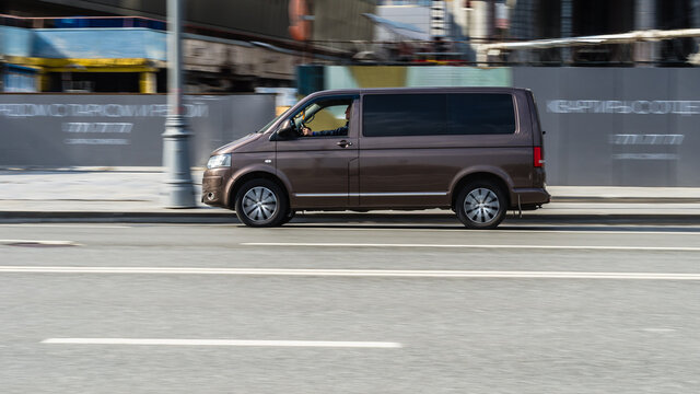Fast moving Volkswagen Transporter T6 on the city road. Brown minivan rides on street. Commercial auto in fast motion with blurred background. speeding in the city concept