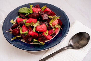 Beetroot, pineapple and chicory salad with olive oil and basil on a plate on a white marble background. Fresh and healthy vegetables concept.