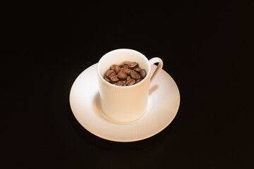 Coffee beans in a white coffee cup on a black background