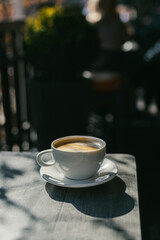 Cup of coffee on a rustic wooden table in a street cafe.