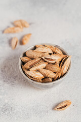 Pile of Almond nuts in a bowl on a white background. Fresh nuts in their shells.