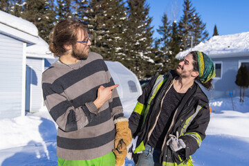 Portrait of two smiling, good willing young men posing ironically for camera with arms up after a...