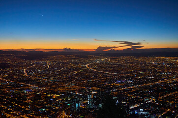 A view of the city of Bogota from the Monserrate hill at dusk, with a beautiful horizon with vibrant blue and orange colours.