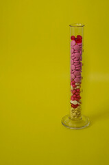 the multicolored tablets are placed in a dimensional glass cylinder for analysis on a green background. pharmaceutical preparations for analysis. Quality control