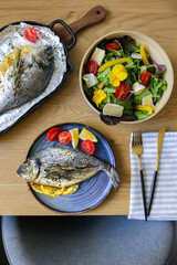 Mediterranean cuisine on the table.Dorada from the oven with salad and cheese.Cheese platter with nuts and salad.Proper nutrition on the table.Vegetables with baked fish.Ready fish.Dorado grill