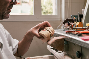 dental technician holding a dental prosthesis skeleton in his hand