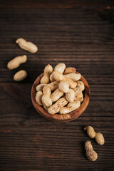 Pile of Peanuts in a bowl on a dark wooden background