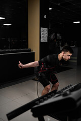 Fototapeta na wymiar Making physical exercises using EMS suit in gym. Sport training in electrical muscle stimulation suit