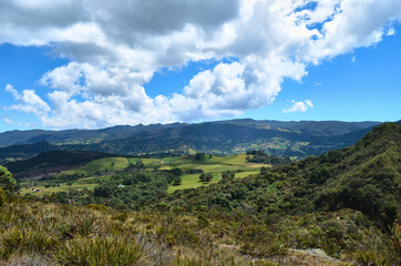 A view of the mountains, green foliage and blue sky at the natural park of Guatavita, located in...