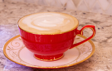 Cappuccino, latte, mocha, macchiato Italian coffee in a delicate red porcelain cup.