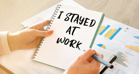 A business woman sitting at a table in a light office holds a notebook with notes in her hands, against the background of business charts and business documents. Close-up, soft light.