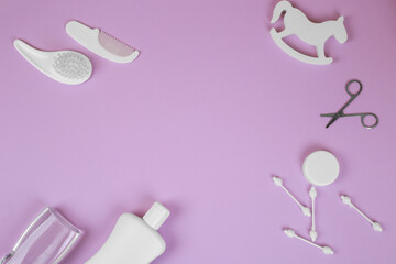 Baby accessories on lavender background, flat lay. Composition with baby accessories and space for text. Baby cotton swabs, scissors, combs, oil, baby rattle