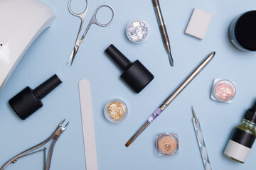 Top view of tools and materials for modern manicure and nail extension. Knolling on a blue...