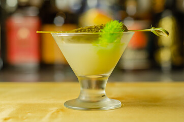 Shaken vodka and pickle juice with ice in shot glass and garnishing with small pickled cucumber and dill