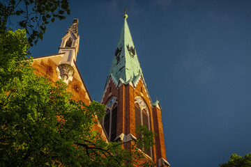 Red brick church with green roof in Tabor area in Ljubljana, lit by morning sun in late spring.