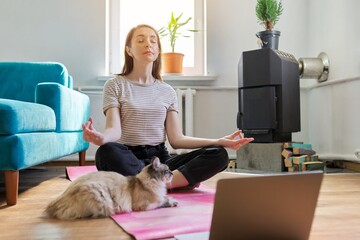 Middle aged woman sitting at home on floor with laptop in lotus position