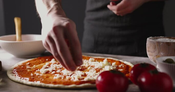 Chef is putting cheese onto piece of dough when making pizza. Cooker applying fresh ingredients while making italian pizza. food and drink 4k footage