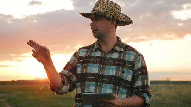 Smart agriculture technology farmer holding tablet with smart technology. Farmer using tablet in field at sunset. Modern Agriculture concept. Innovation technology application in agricultural.