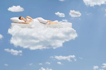 Foto op Canvas Young woman sleeping on a floating mattress up in the clouds © Ljupco Smokovski