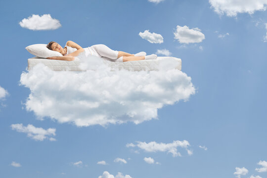 Young woman sleeping on a floating mattress up in the clouds