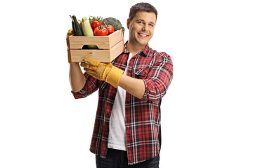 Young male farmers carrying crate with vegetables on his shoulder and smiling