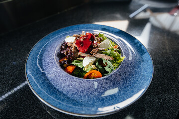 Prepare a delicious fresh salad of tomato greens, cheese, veal and cashew nuts. Delicious healthy food.