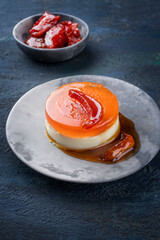 Modern style traditional blancmange almond pudding with quince moraba ye beh and quince gelee compote coulis served as close-up on a design plate on black background