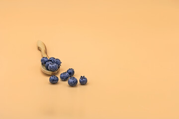 Wooden spoon filled with blueberries and blackberries, isolated on yellow background