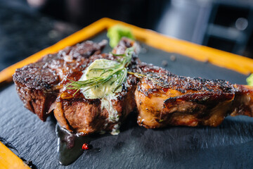 Close-up of a beautifully grilled juicy steak with butter and seasonings. Grilled meat in a restaurant.