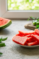 Slice of fresh watermelon in plate near window on white table