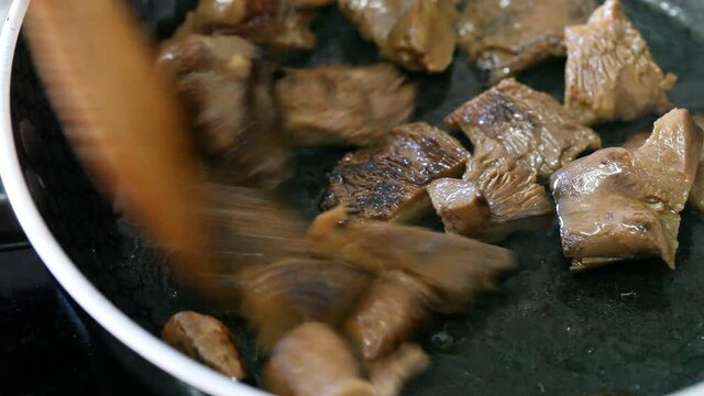 Chopped mushrooms (Lactarius deliciosus) are fried in black pan, cooking and kitchen concept