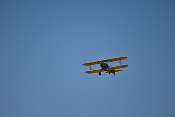 A world war II biplane flying in the blue sky