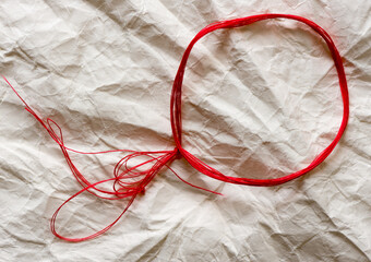 red thread circle on an off white crumpled paper background