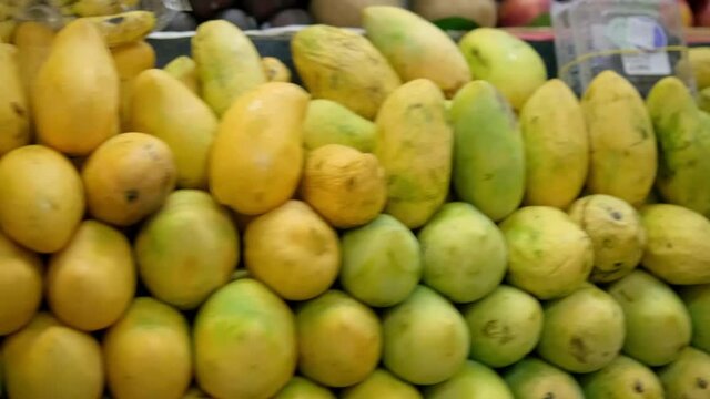Close-up of colorful fruit stand with pile of different mangoes