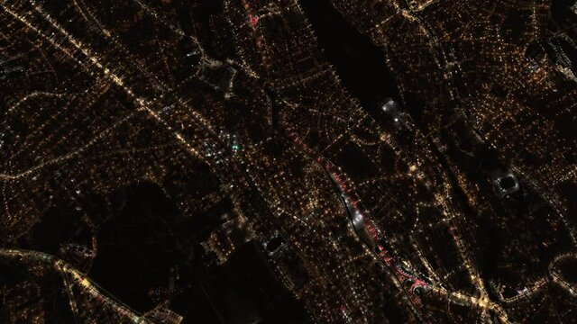 Top view of a city at night. Satellite view of roads, buildings and cars with flickering lights.