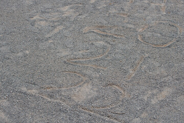 numbers 20, 21, and 22 drawn with a stick on fine gravel ground