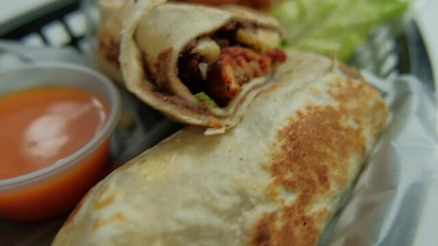 Spicy pork burritos and lettuce in a plastic basket
