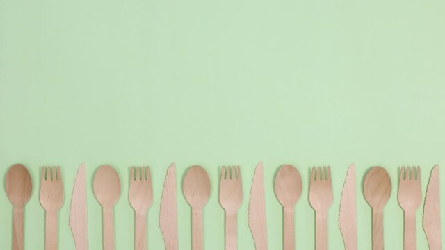 Eco friendly zero waste kitchen utensils cutlery ordering on bottom of light green background. Stop motion