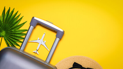 Sea background. Travel accessories with suitcase, white plane, palm leaves in minimal trip vacation concept on yellow background. Tranquil beach scene with copy space.