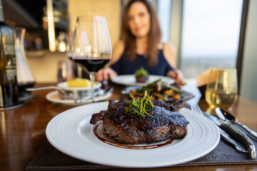 Gourmet grilled ribeye steak dinner with red wine on a date with a woman. 