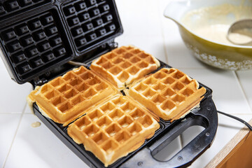 Belgium Waffle cooking on a hot griddle for breakfast