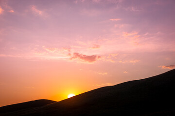 The sun is setting behind the mountains.