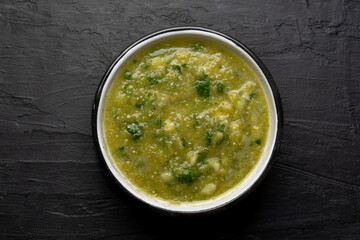 Mexican piquant green sauce with cilantro and onion on dark background