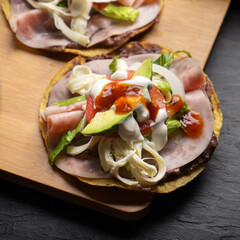 Corn toast with ham and Oaxaca cheese on dark background. Mexican food