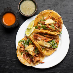 Pork tacos called al pastor with pineapple on dark background. Mexican tacos