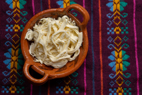 Shredded Oaxaca cheese also called quesillo on rustic background. Mexican food