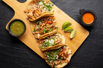 Pork tacos called al pastor with pineapple on dark background. Mexican tacos